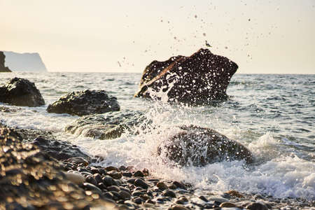 Splashing waves crash against rocks on Jasper Beach at Cape Fiolent at sunriseの写真素材