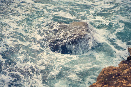 Sea waves bumping against the rocky shoreの写真素材