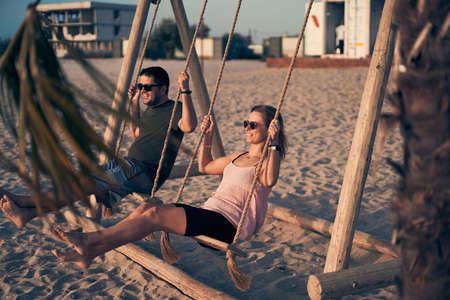 Young attractive couple swinging on seesaw on the beach.の写真素材