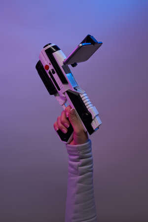 Hand with a blaster for games with augmented reality on a purple background.の写真素材
