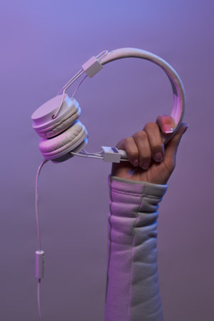 Hands with white headphones on violet background.の写真素材