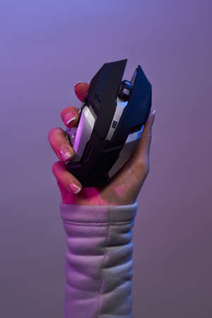 Hand with pc mouse on violet background.