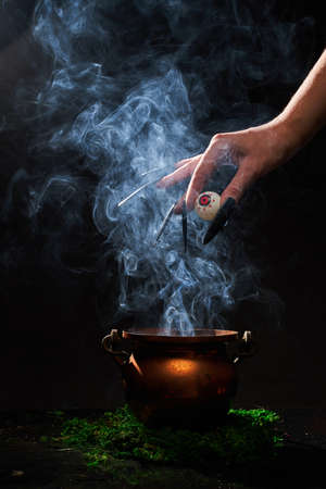 The witchs hand put her eye in the smoking cauldron.の写真素材