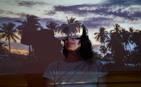 Woman uses virtual reality glasses to go to another point of light and see palms.の写真素材