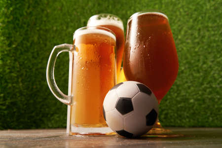 Four glasses of beer with soccer ball on the green grass background.の写真素材
