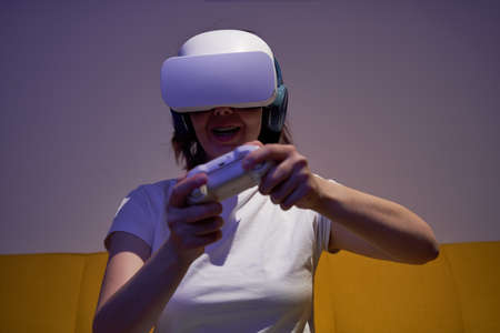 Woman with virtual reality headset and joystic is playing game.の写真素材