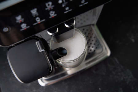 Freshly brewed latte is poured from the coffee machine into glass cups.の写真素材