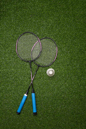 Badminton racket and shuttlecock on green grass background.