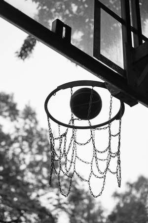 Street basketball ball falling into the hoop. Black and white photo.