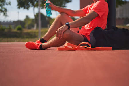 Sport man in sportive clothes relaxing after workout at the stadium, runner taking break after running sport.の写真素材