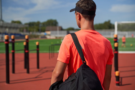 Back view of sportsman with bag standing at the open stadiumの写真素材