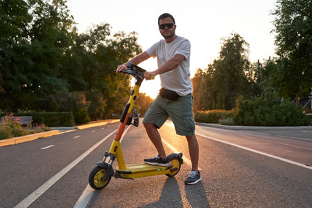 Man is riding on electric scooter or e-scooter on the street on the sunset.の写真素材