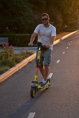 Man is riding on electric scooter or e-scooter on the street on the sunset.の写真素材