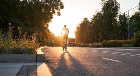 Man is riding on electric scooter or e-scooter on the street on the sunset.の写真素材