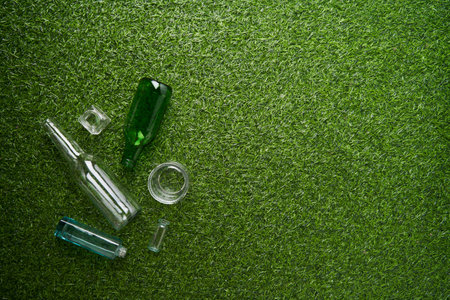 Separate collection of glass garbage. Recyclable glass waste on green grass background.の写真素材