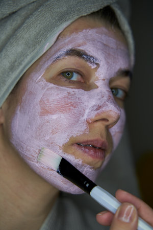 Woman with a towel over your head inflicts brush face mask of therapeutic clay.の写真素材