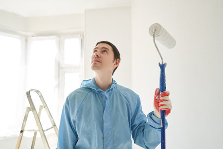 Man stand in the room with paint roller in his handの写真素材