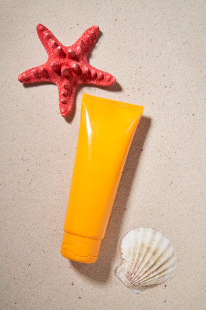 Summer sunscreen cream on sand background with starfish and shell.の写真素材