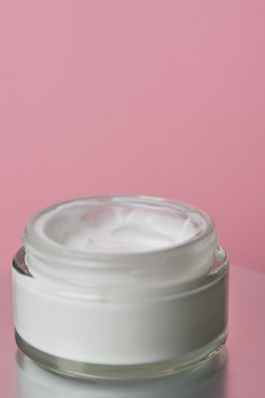 Glass jar with white face cream moisturiser on pink background.の写真素材