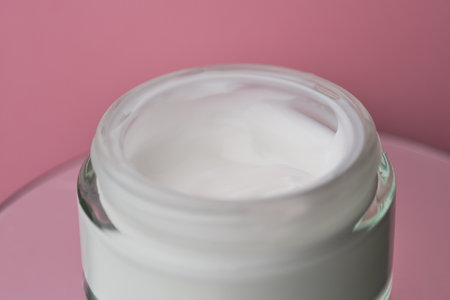 Glass jar with white face cream moisturiser on pink background.の写真素材
