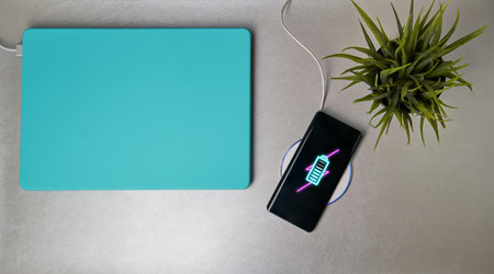 Charging mobile phone battery with wireless charging device on the table.
