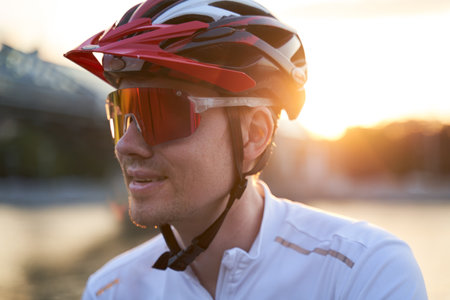 Man is wearing protective helmet, sunglasses and sportswear during evening ride in city.の写真素材