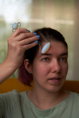 Woman is massaging her face roller.
