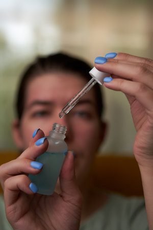 Woman is holding and opening bottle with moisturizing face serum.