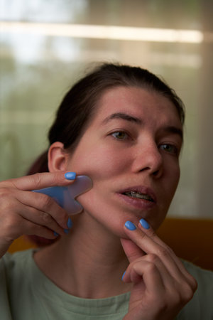 Woman is massaging her face scraper gua sha.の写真素材