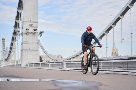 Man riding on bicycle across the bridge in the city.の写真素材