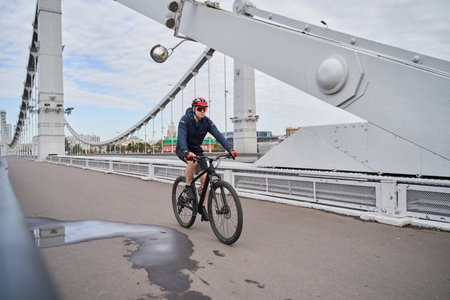 Man riding on bicycle across the bridge in the city.の写真素材