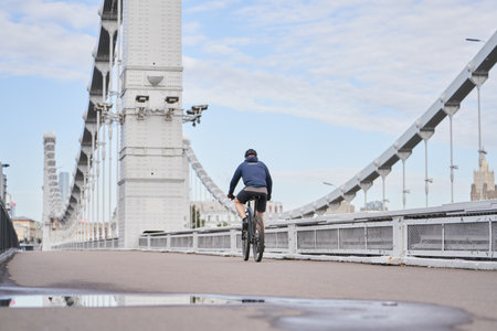 Man riding on bicycle across the bridge in the city.の写真素材