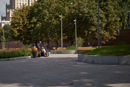 Man in a bicycle helmet sits on a bench and looks at his phone, resting while cycling in the cityの写真素材