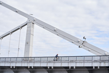 Man riding on bicycle across the bridge in the city.の写真素材