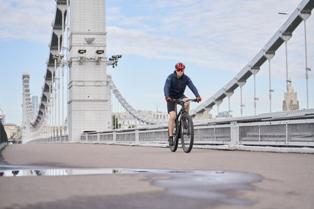 Man riding on bicycle across the bridge in the city.の写真素材