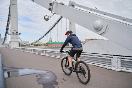 Man riding on bicycle across the bridge in the city.の写真素材