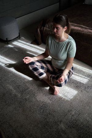 Woman Practicing Meditation in Sunlit Roomの写真素材