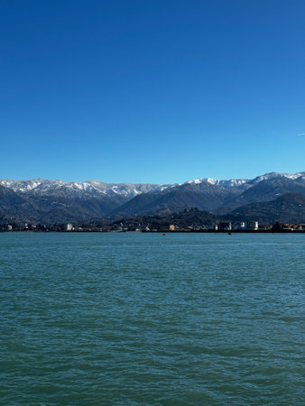 Wide View of Snowy Mountains and Coastal Waters Under Clear Skyの写真素材