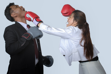 Portrait of professional businessman in suits and boxing gloves kicking his rival,isolated on gray backgroundの写真素材