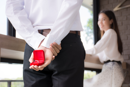 Men holding a wedding band box behind to surprise a girlfriend on Valentine dayの写真素材