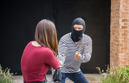 Male robber robbing a handbag threatening with knife to scared Asian woman,criminal conceptの写真素材