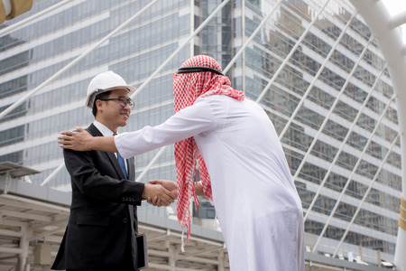Arabic businessman shaking hands Asian Engineering over a deal negotiation to success with city backgroundの写真素材
