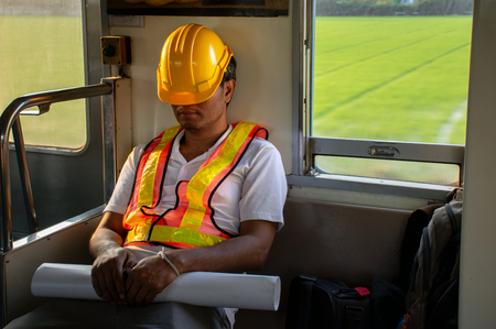 Picture of Asian engineer wearing safety helmet tired fall asleep during working hours in...