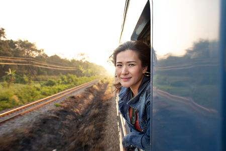 Portrait of young beautiful Asian woman traveling by train looking out from the windowの写真素材