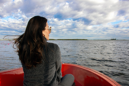 Back view of the young Asian woman enjoy on the boat and looking forward into lagoon