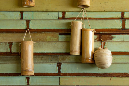 Bamboo tube for drinking water. Hanging on a wooden wall