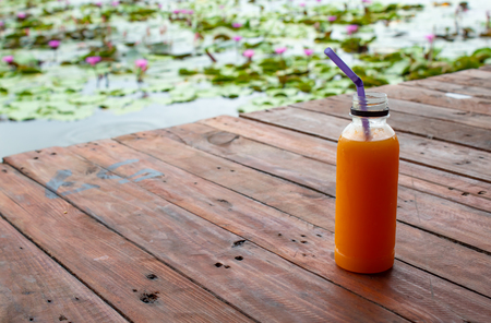Orange juice fresh and cool in the plastic bottle on wooden table.の写真素材