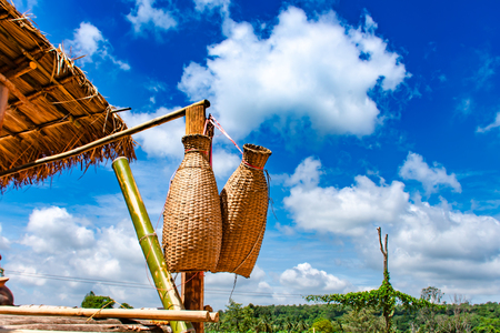 Fishing creel, Bamboo basket hang on the terrace of wood and bright blue sky.の写真素材