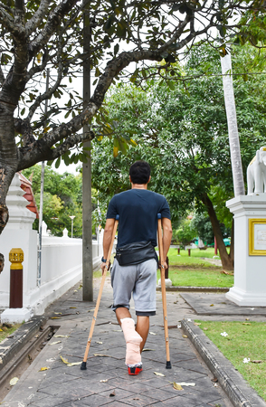 The men used wooden crutches walks in the garden.の写真素材