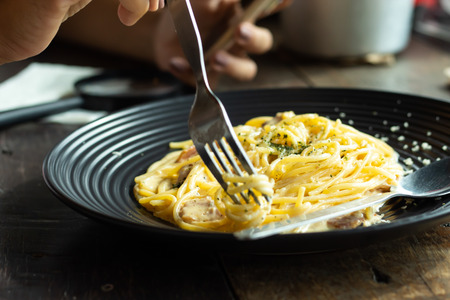 The spaghetti, fried cheese on a black plate on the table.の写真素材